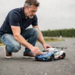 Passionné de modélisme RC ajustant une voiture télécommandée 1/10 sur un circuit extérieur en Vendée