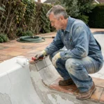 Artisan appliquant un revêtement imperméable sur les parois d'une piscine vide en cours de rénovation
