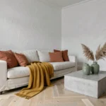 Salon scandinave blanc et gris avec coussins terracotta, vases vert sauge et plaid moutarde pour sublimer l'intérieur
